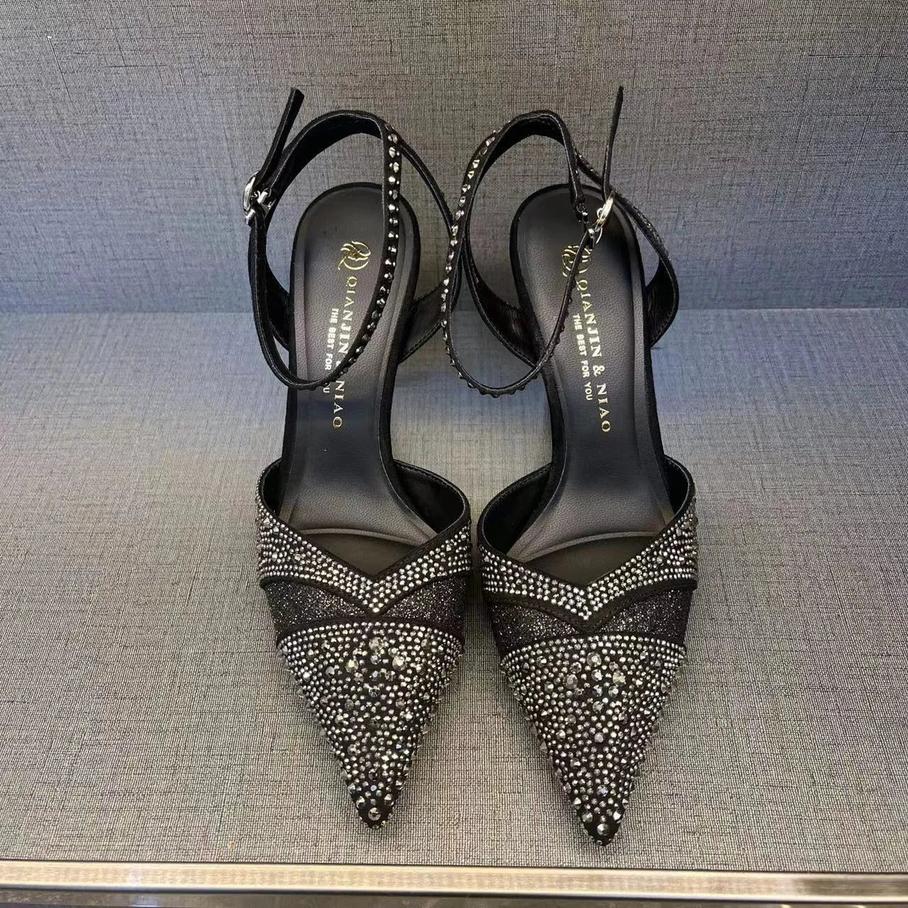 Women's black pointed-toe stiletto heels with a hollow-out design and red sole.