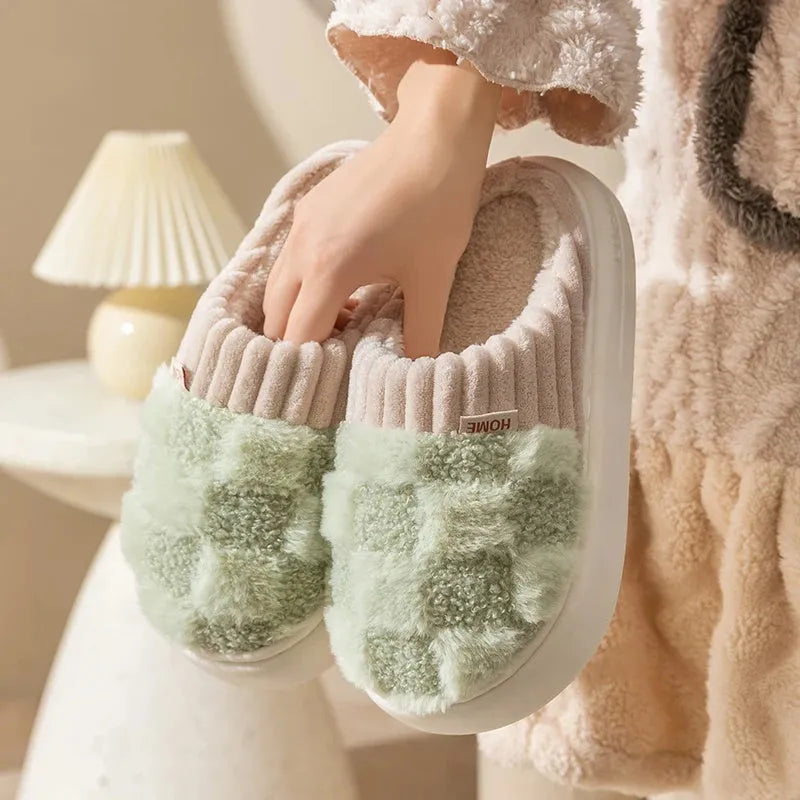 Plaid pattern women's plush indoor slippers in grey with a round toe and flat heel on a non-slip sole.