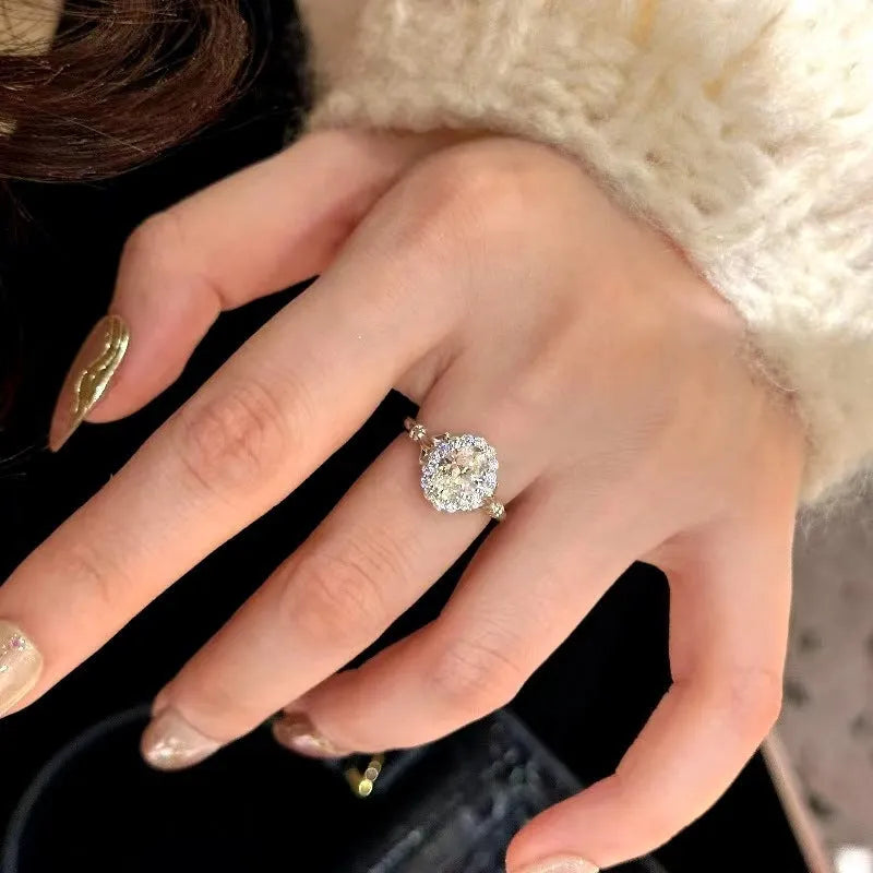 Silver geometric ring with an elliptical diamond centre on a model's hand, showing adjustable opening.