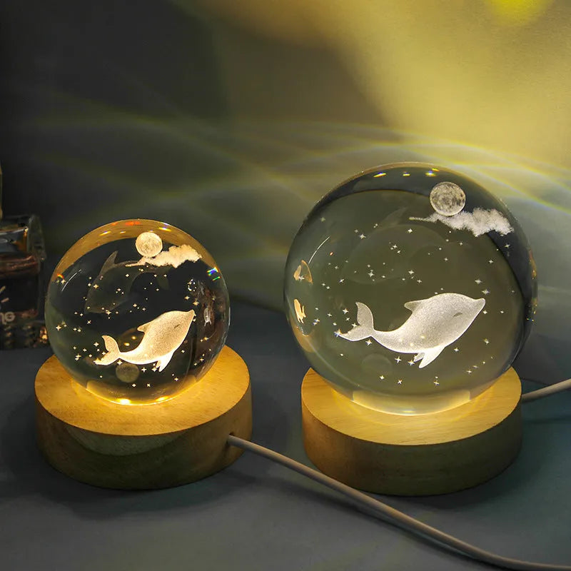 Transparent crystal ball night lamp with 3D carved jellyfish design, lit with soft blue glow on a round base.