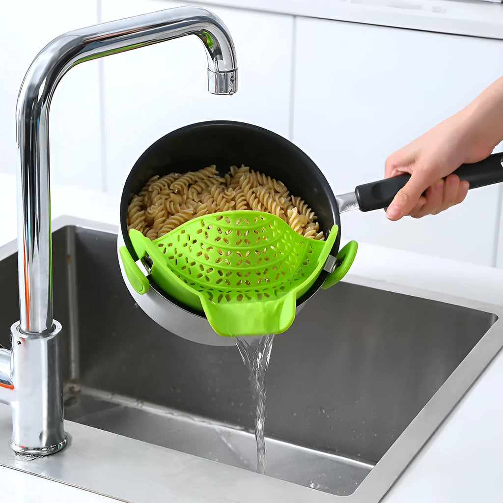 Green silicone pot drain stopper with stainless steel insert on a kitchen countertop.