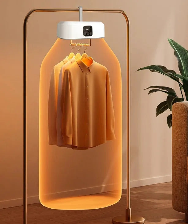 White foldable cylindrical laundry dryer with remote control on a table.