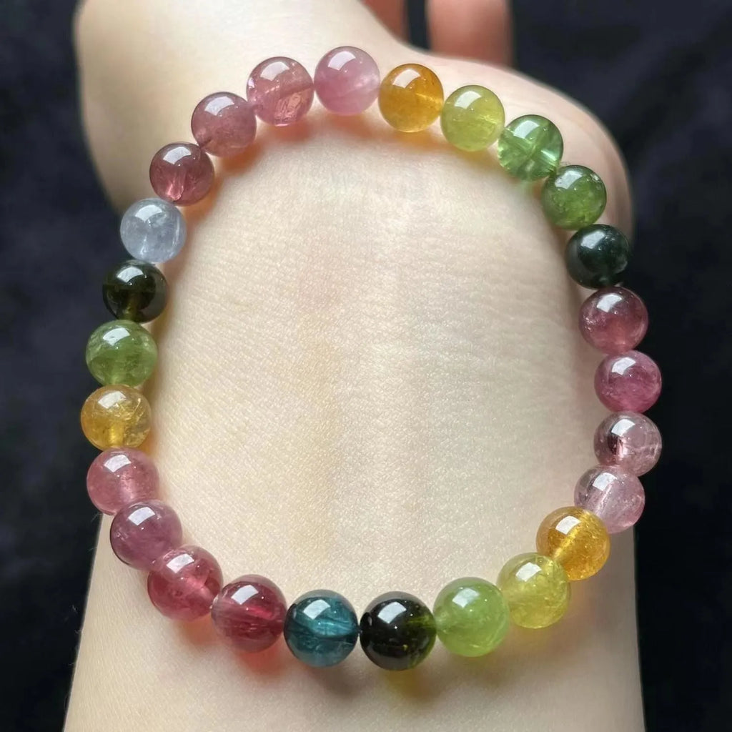 Natural colour tourmaline bracelet with four-leaf clover charm and pearl pendant on wrist