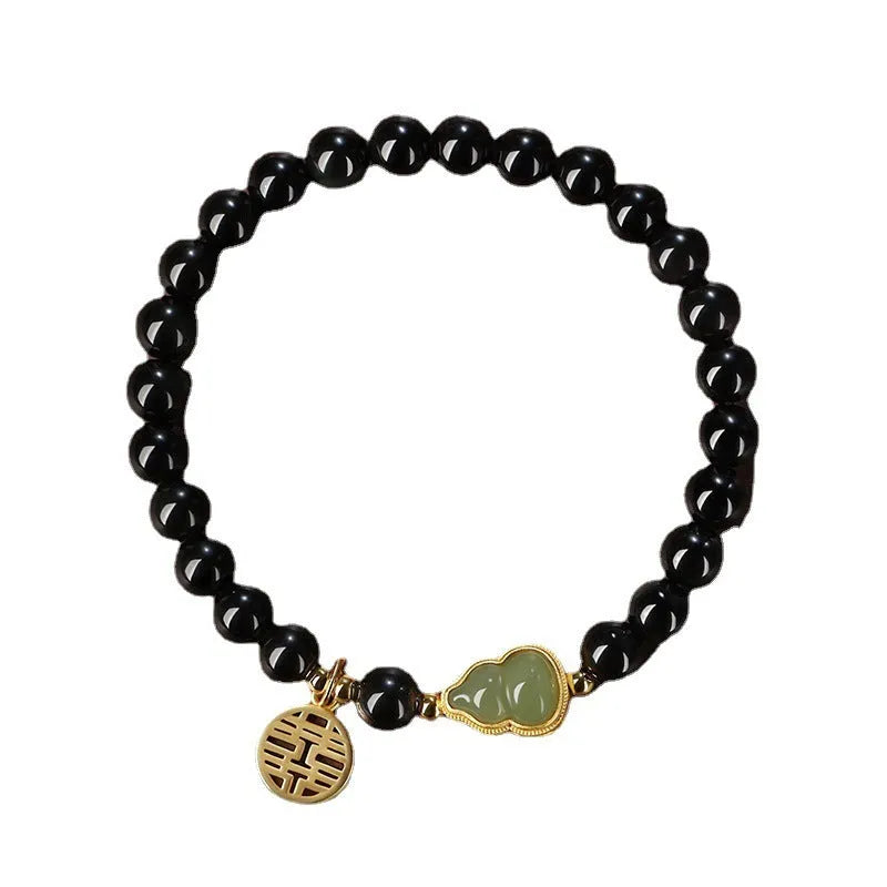 Black obsidian bead bracelet with a carved Hetian jade gourd charm in geometric pattern.