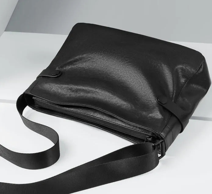 Men's black genuine leather and cowhide crossbody messenger bag with waterproof function and patchwork detail.