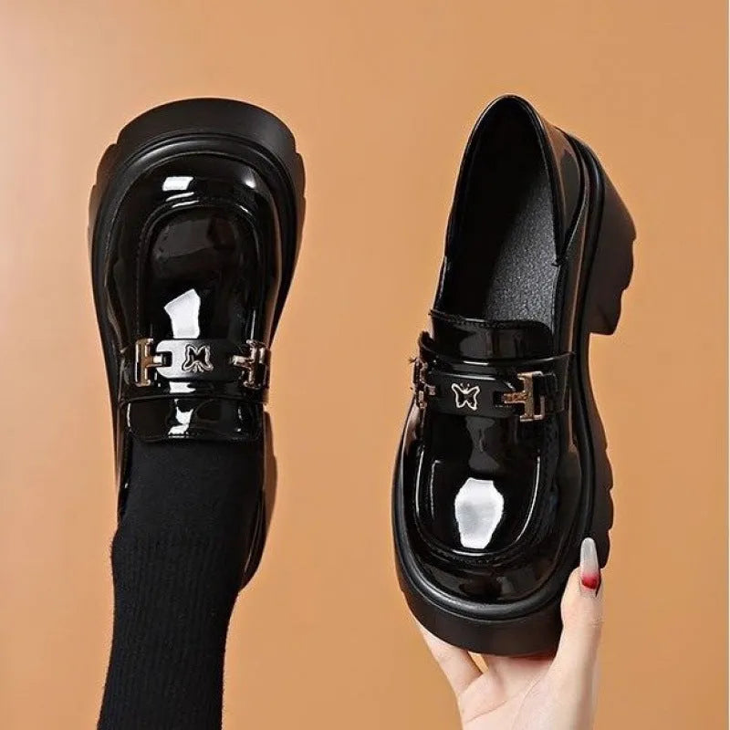 Black slip-on leather shoes with a chunky square heel and a skull pattern on the upper.