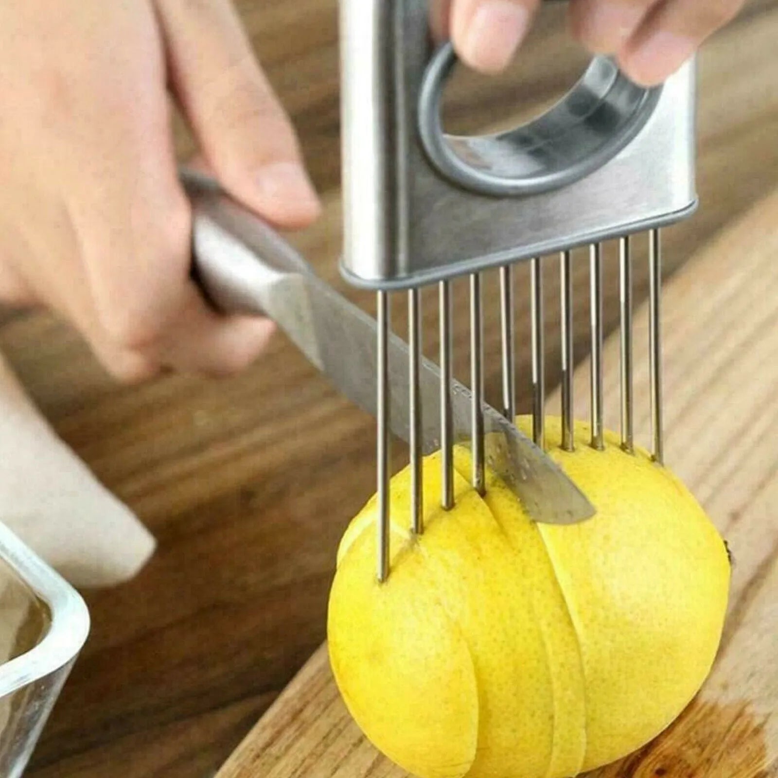 Stainless steel onion holder slicer with sharp prongs and a separate finger guard on a kitchen counter.