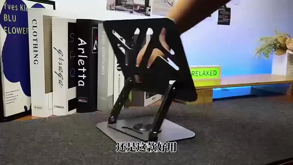 Black foldable laptop stand with metal grid design and height adjustment, placed on a desk with a laptop