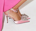 Women's pink satin sandals with heart-shaped rhinestone and cross-belt ankle strap on a pointed toe.