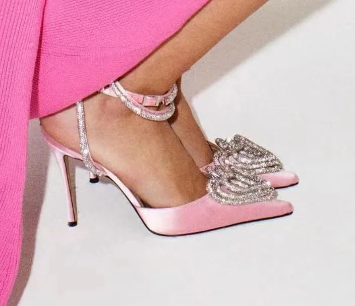 Women's pink satin sandals with heart-shaped rhinestone and cross-belt ankle strap on a pointed toe.