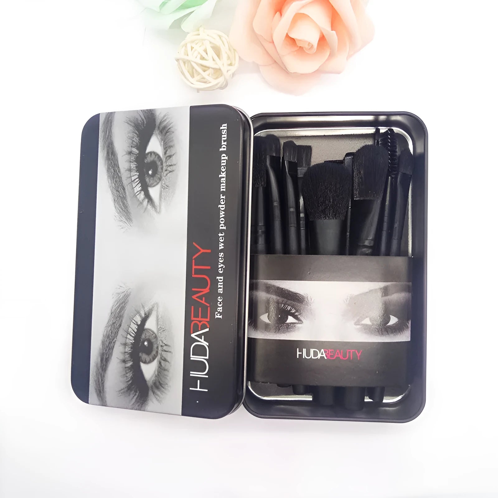 12 makeup brushes with corrugated silk nylon bristles and wooden handles in a black tin box on a flat surface.