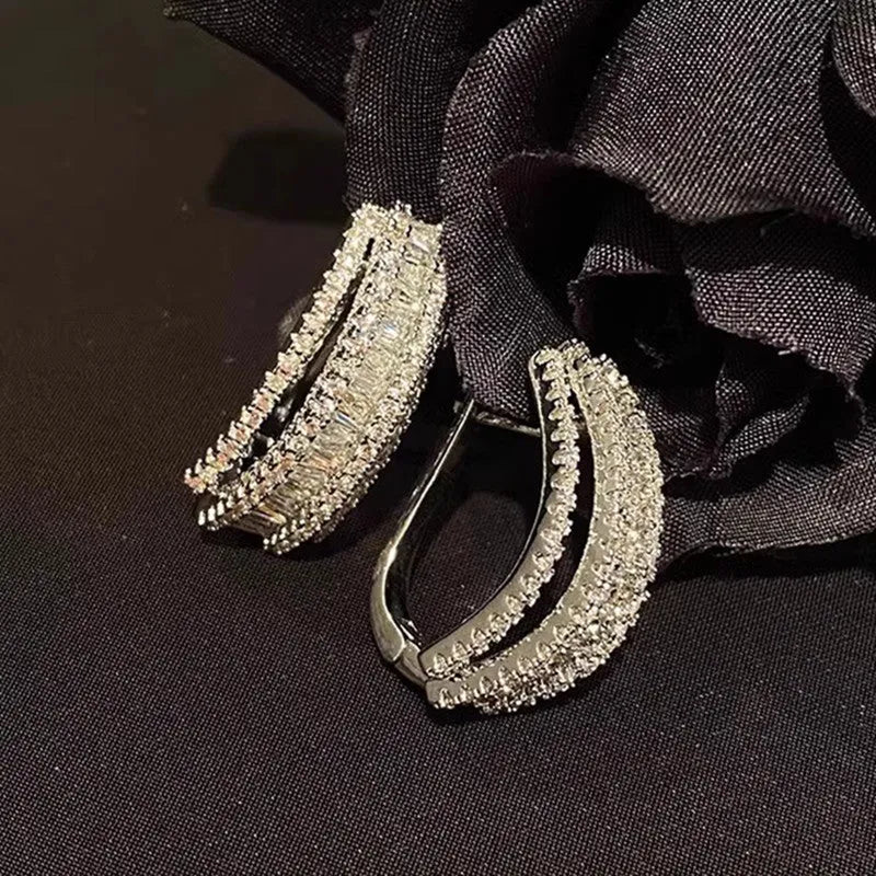 A pair of women's geometric stud earrings in white gold colour with a central inlaid zircon stone.