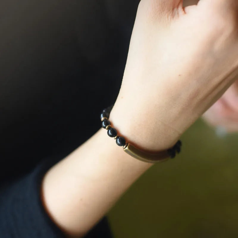 Layered ethnic bracelet with gemstone beads and brass details on a wrist, showing adjustable unisex design.