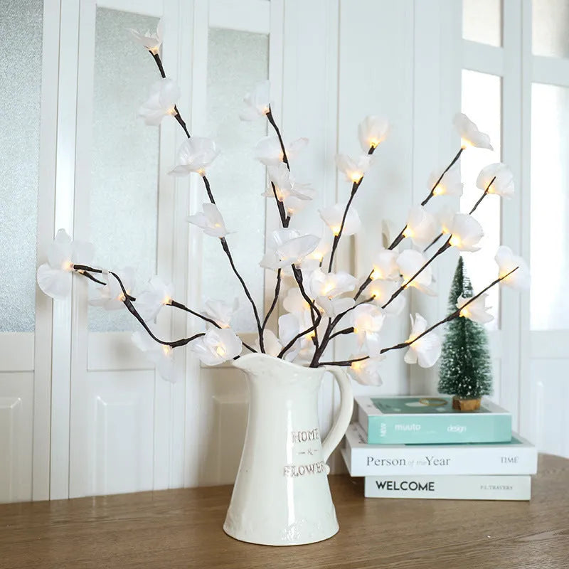 Pink fabric-covered LED Phalaenopsis orchid branch light, 65cm long, with warm white bulbs illuminated on a dark surface.