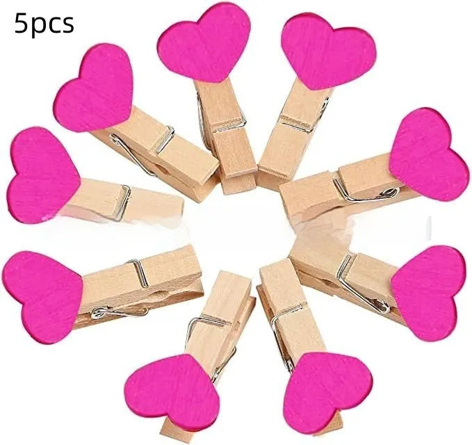 Five handmade wooden heart-shaped clips in red, pink, white, and yellow colours on a table.
