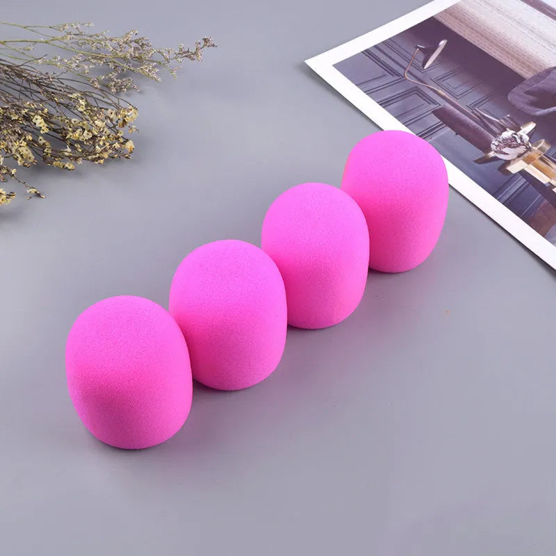 Four multicolored foam microphone windshields for handheld stage microphones on a grey background.