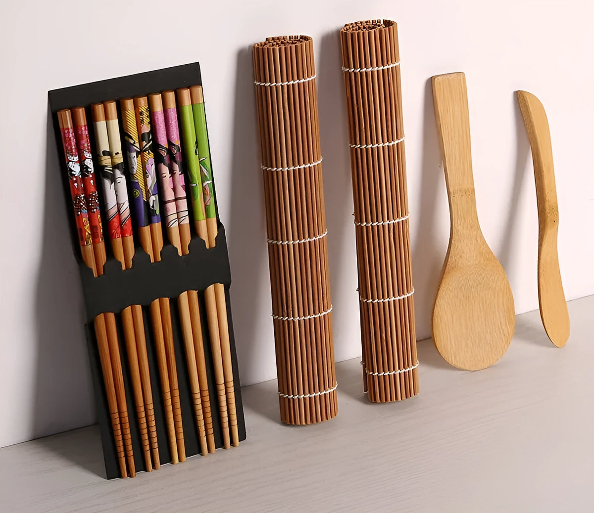 White sushi tool set with bamboo rolling mat and spatula on a kitchen counter