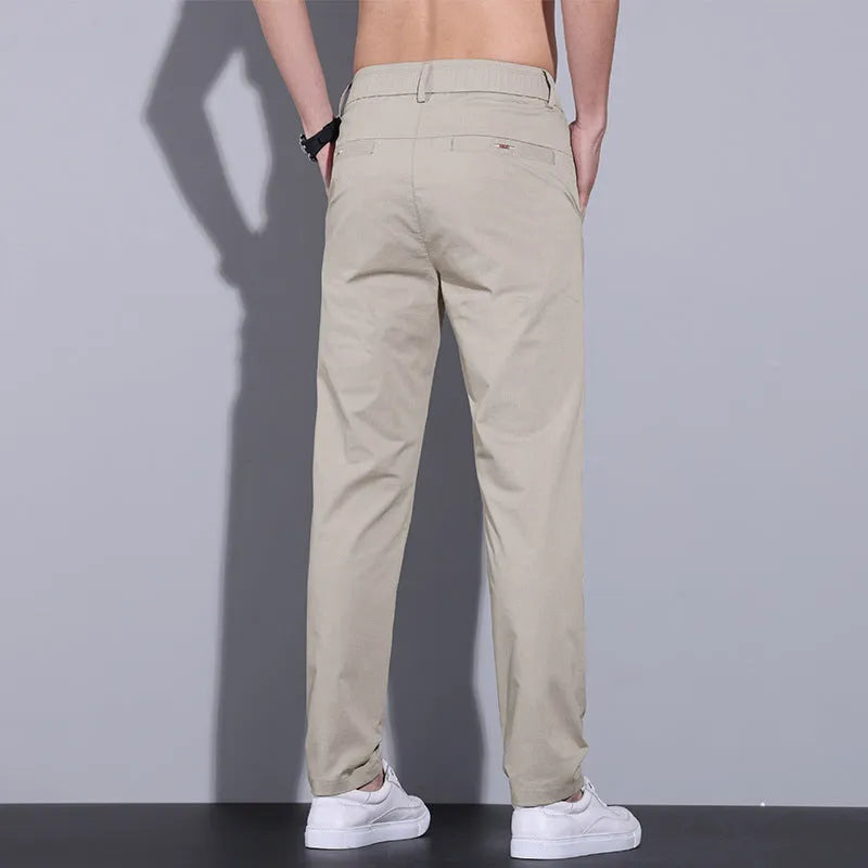 Men's straight-leg slim fit cotton trousers in light khaki colour on a hanger.