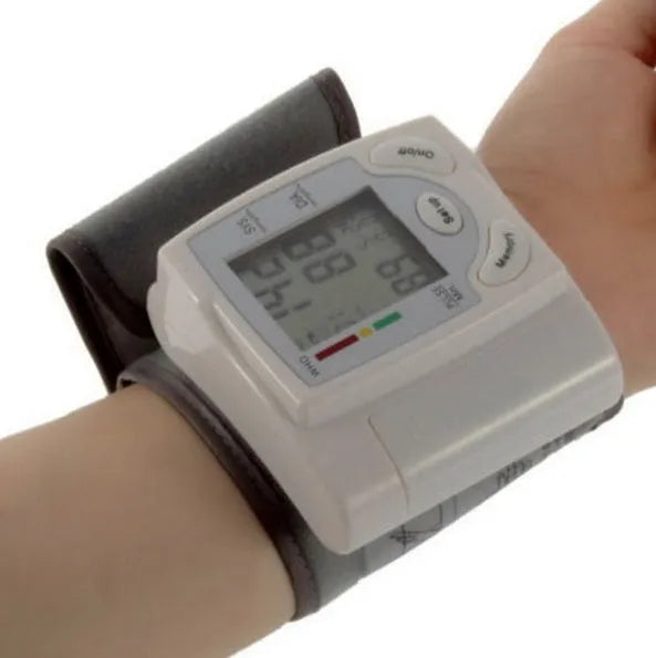 Grey portable wrist blood pressure monitor with digital display on a wrist.
