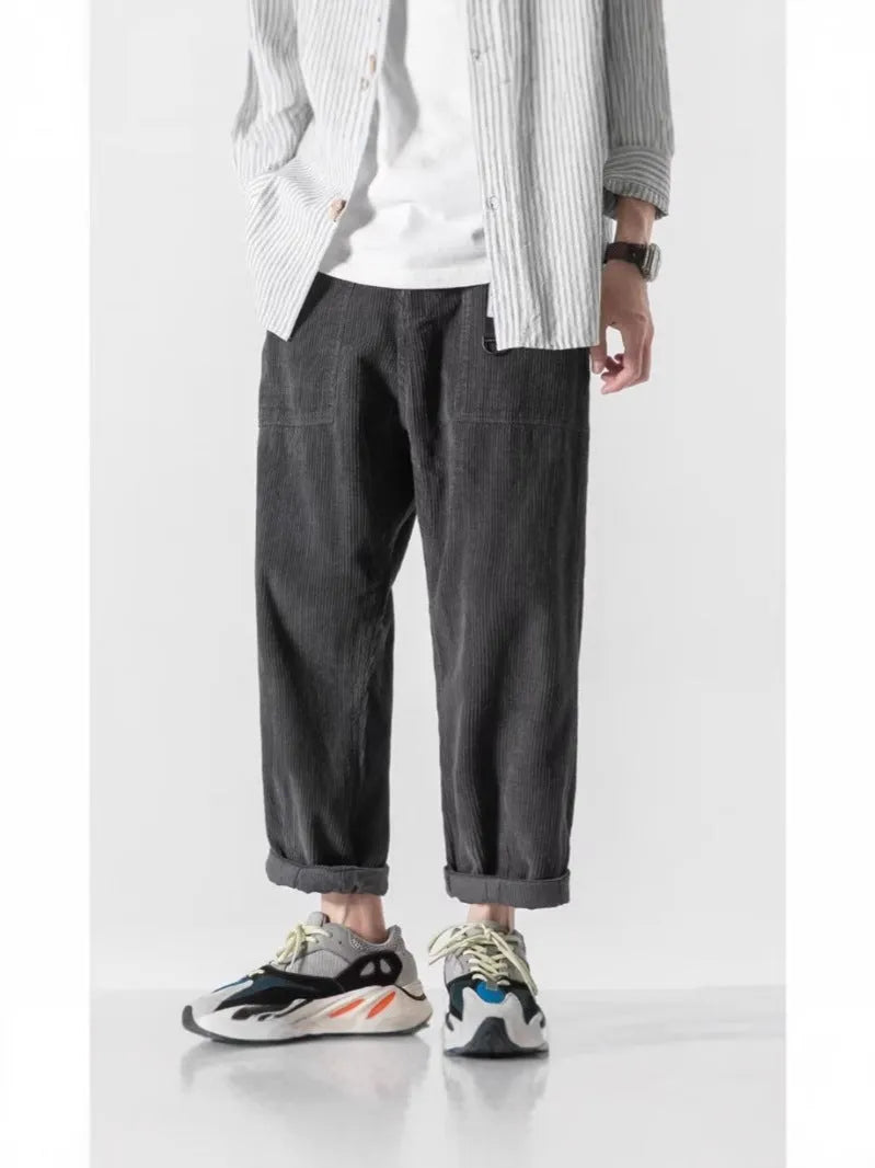 Man wearing loose straight tapered trousers in dark grey, showcasing the straight leg and relaxed fit.
