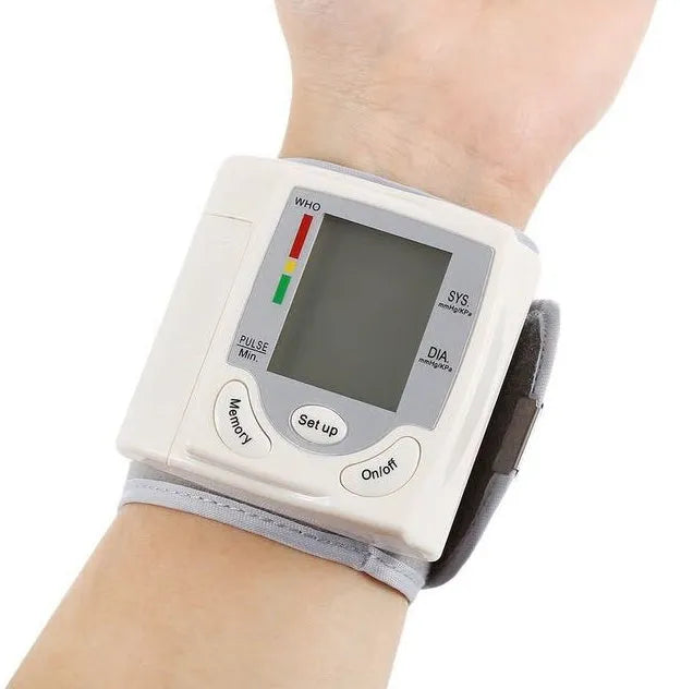 Grey portable wrist blood pressure monitor with digital display on a wrist.