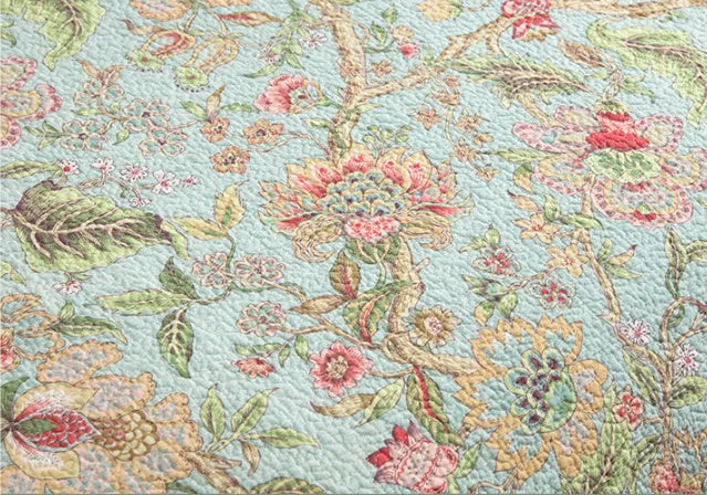 Blue American floral pattern quilted cotton bedspread set on a bed, showing pillowcases.