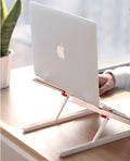 White foldable laptop stand bracket for Apple MacBook on a desktop.