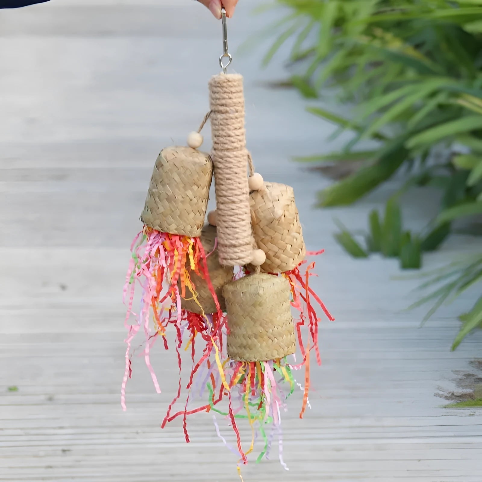 Wooden parrot chewing toy with colourful shredded paper decorations and sisal rope attachments