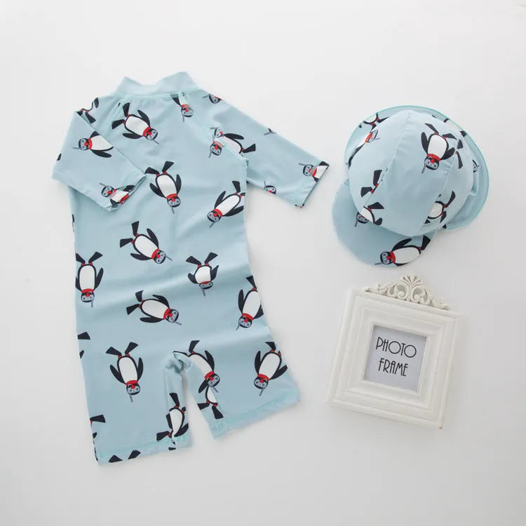 Toddler boy wearing a penguin print long sleeve one-piece swimsuit and matching swimming cap.