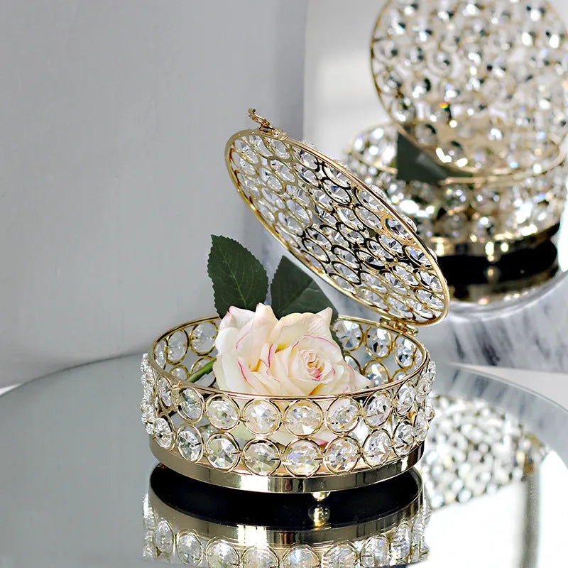 Crystal clear glass jewelry box with French gold metal frame on a table.