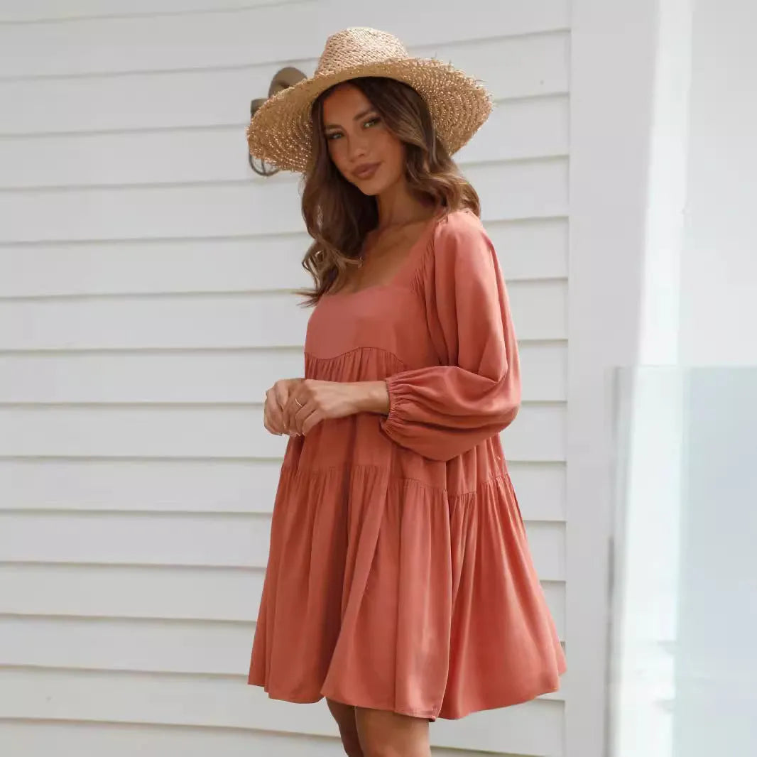 Orange children's backless dress with square collar and puff sleeves on a hanger.