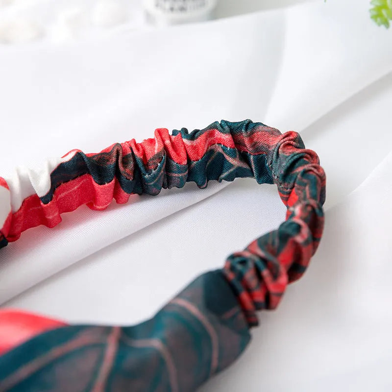 Red cloth headband with banana leaf and cross hair decorative pattern.
