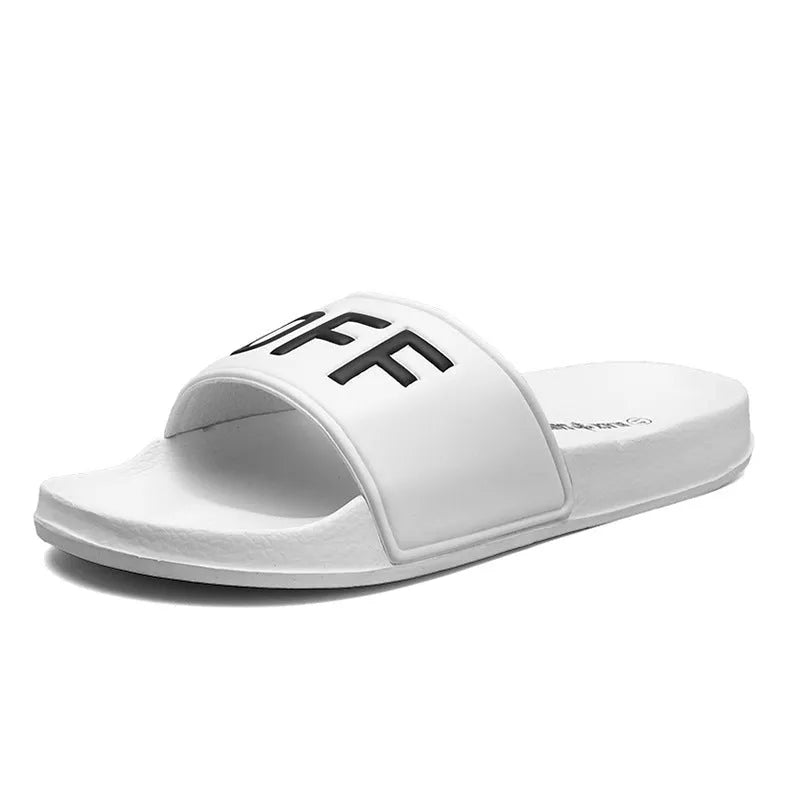 Large black and white open-toe men's slippers with rubber soles, shown on a wooden floor.