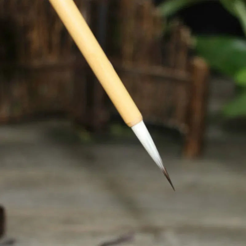 Four Chinese calligraphy brushes with thin gold bodies and natural hair bristles in pine branch colours