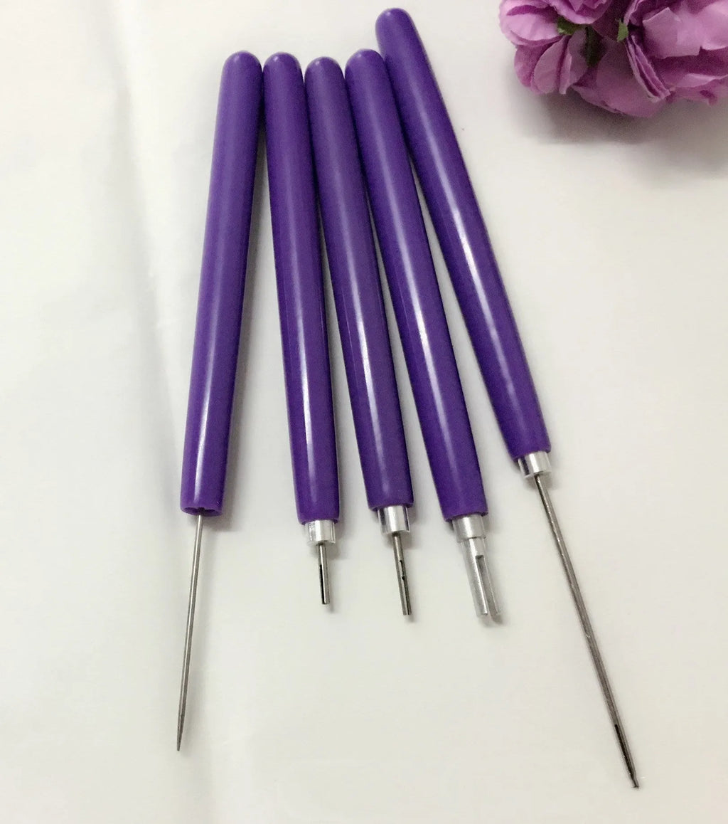 Five purple quilling pens with slotted tips and a stylus laid out on a surface