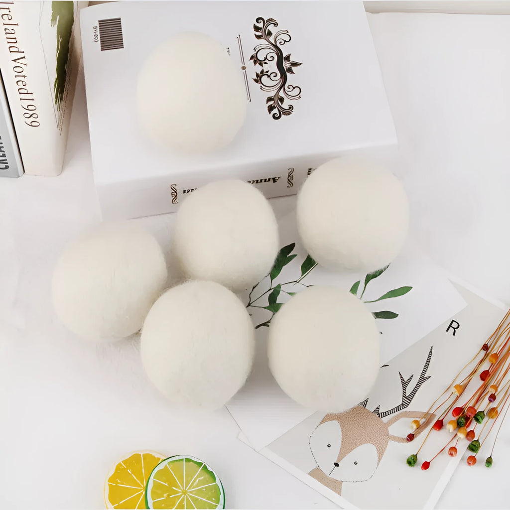 Set of 100% wool felt laundry drying balls in various sizes next to a plain cotton storage bag.