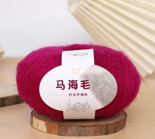 A ball of mohair yarn in a selected colour next to a hand-woven scarf example, showcasing the DIY kit.