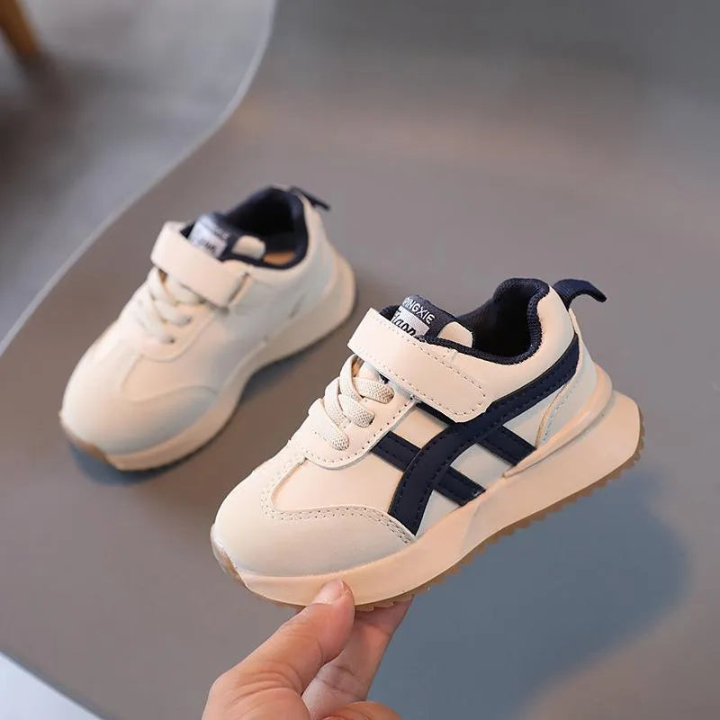 Children's white velcro sneakers with synthetic leather upper and rubber sole on a neutral background.