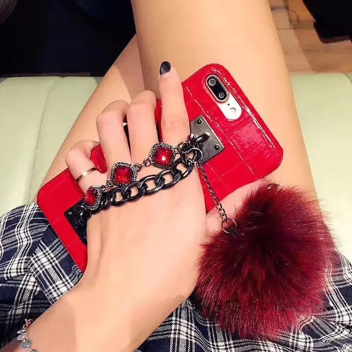 Red iPhone case with fox fur ball decoration and rhinestone studded design