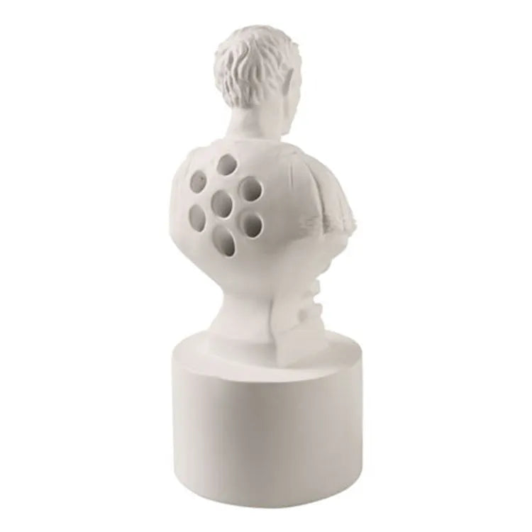 White resin sculpted character pen holder on a desk, holding pens and pencils.