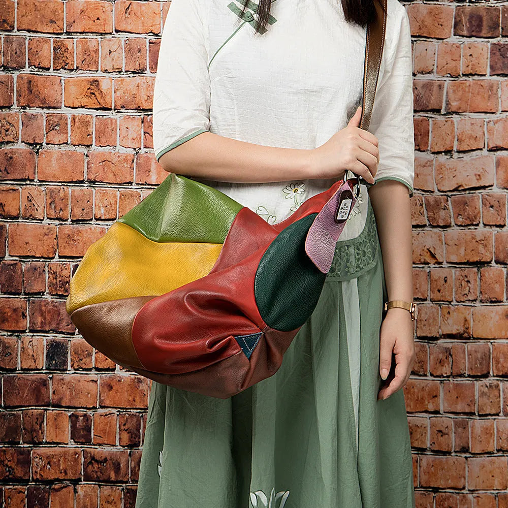 Brown cowhide leather travel bag shown as a crossbody style, with stitching details and enough space for a laptop and magazines.