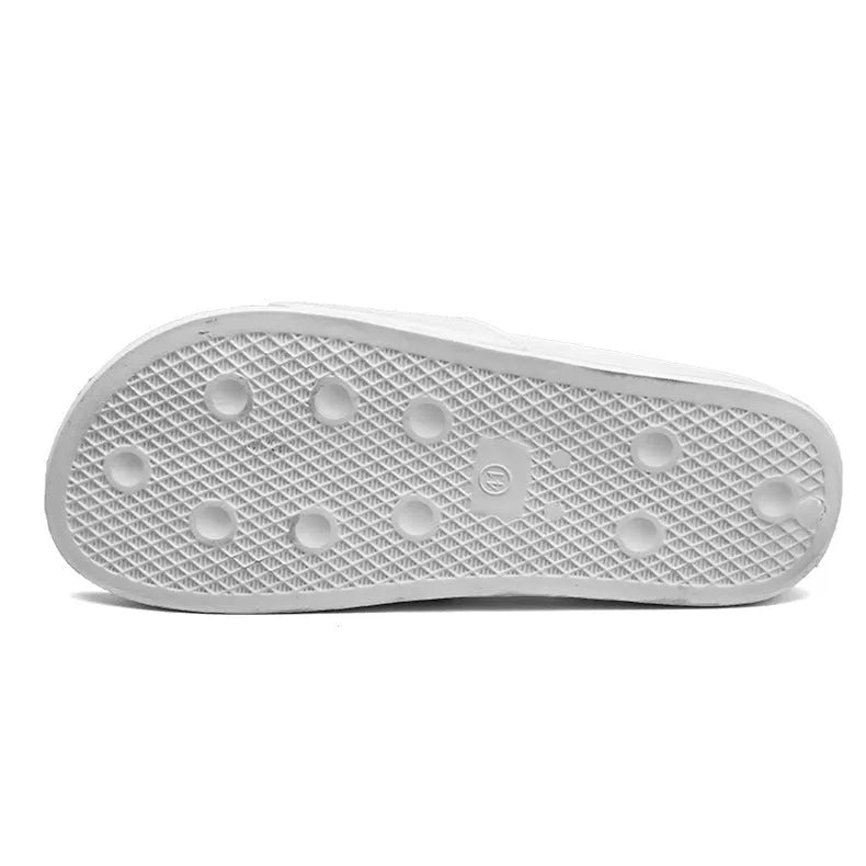 Large black and white open-toe men's slippers with rubber soles, shown on a wooden floor.