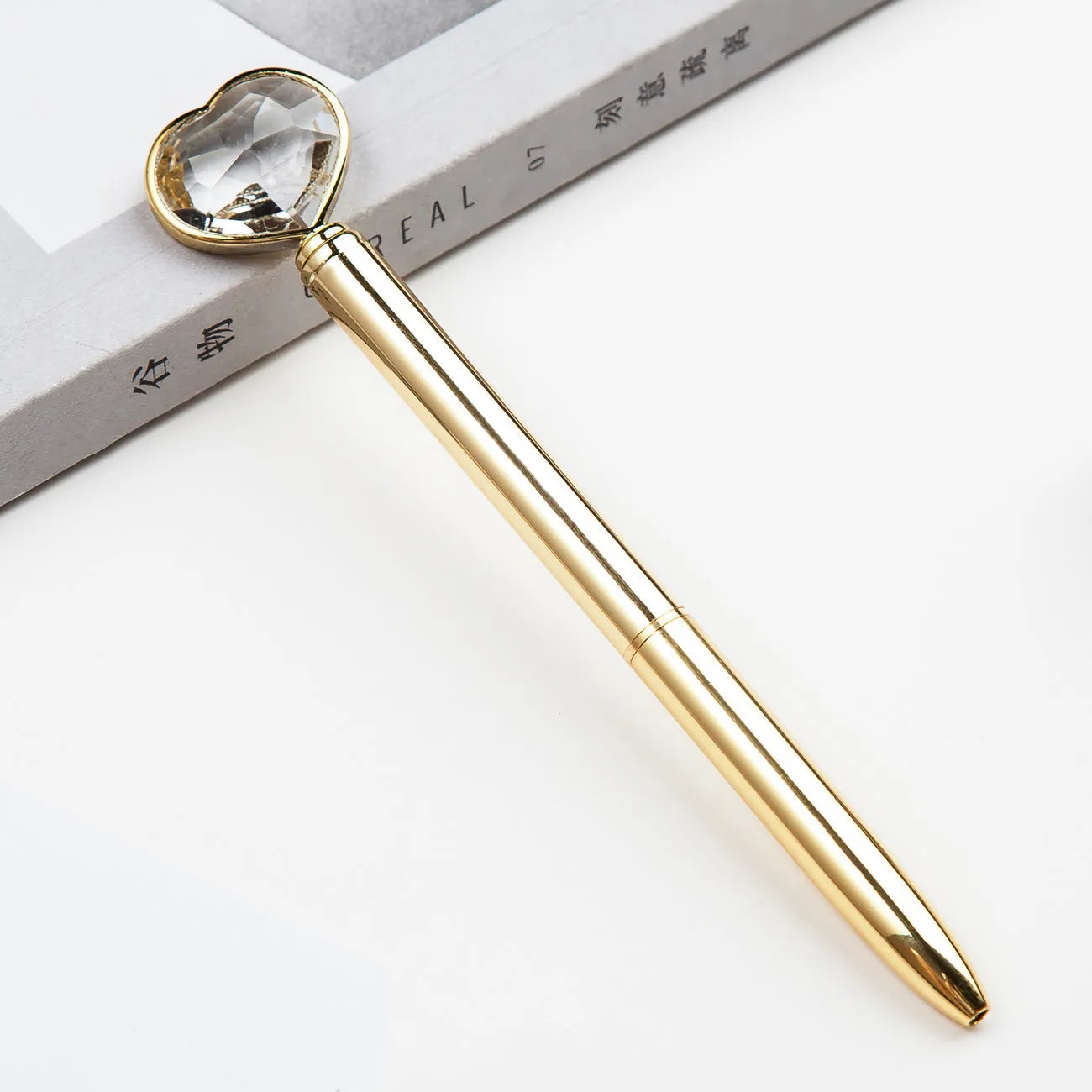 Golden metal pen with crystal love ball and diamond decoration on a white background