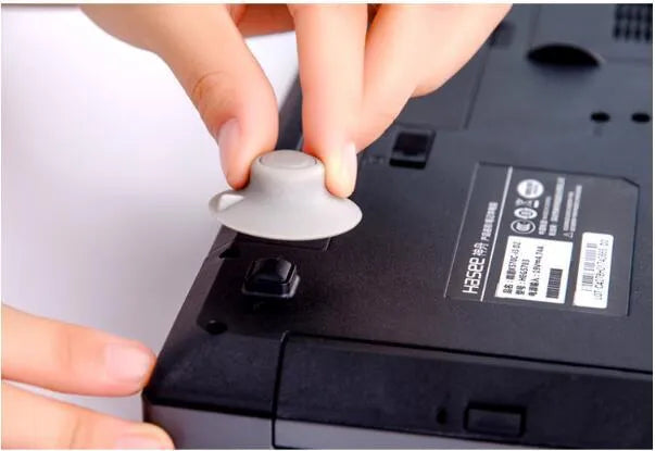 Four grey plastic laptop cooling pads with silicone feet, two large and two small, on a wooden desk.