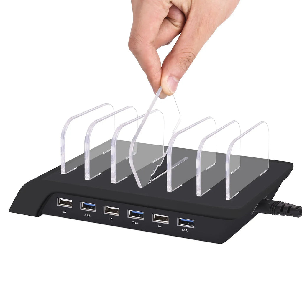 Six-port USB mobile phone charging stand in silver with multiple phones and tablets inserted, on a wooden desk