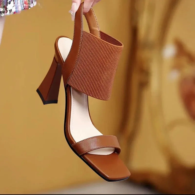 Women's black high heel sandals with a thin elastic strap across the foot.