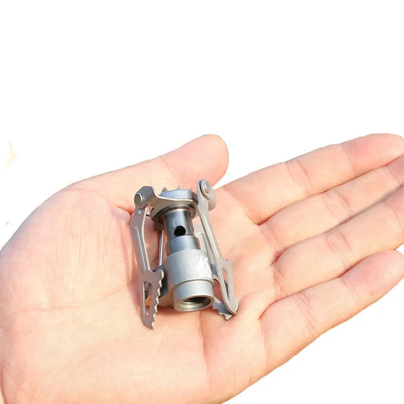 Compact portable gas camping stove with one-piece cast iron burner on a green background.