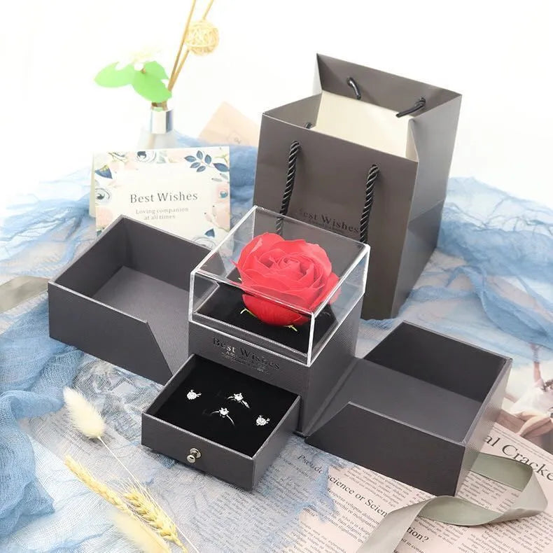 Blue jewellery gift box open to show a plastic eternal rose inside, with space for accessories.