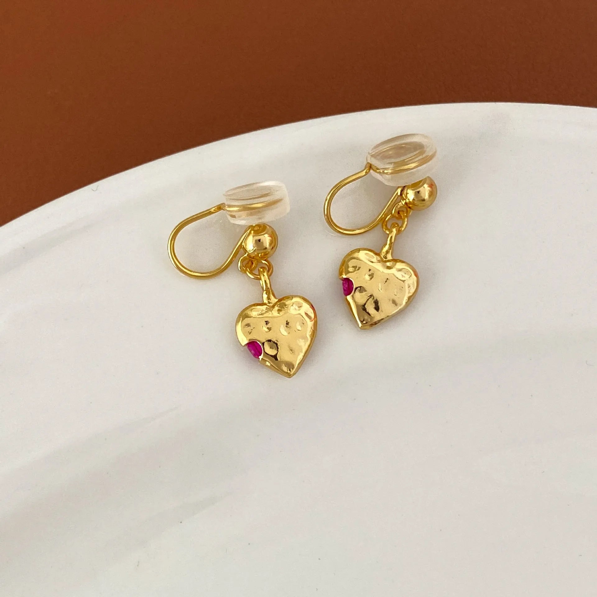 Pair of simple heart-shaped copper earrings with electroplated finish, available as ear clips or studs