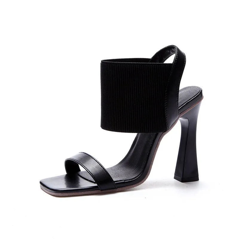 Women's black high heel sandals with a thin elastic strap across the foot.